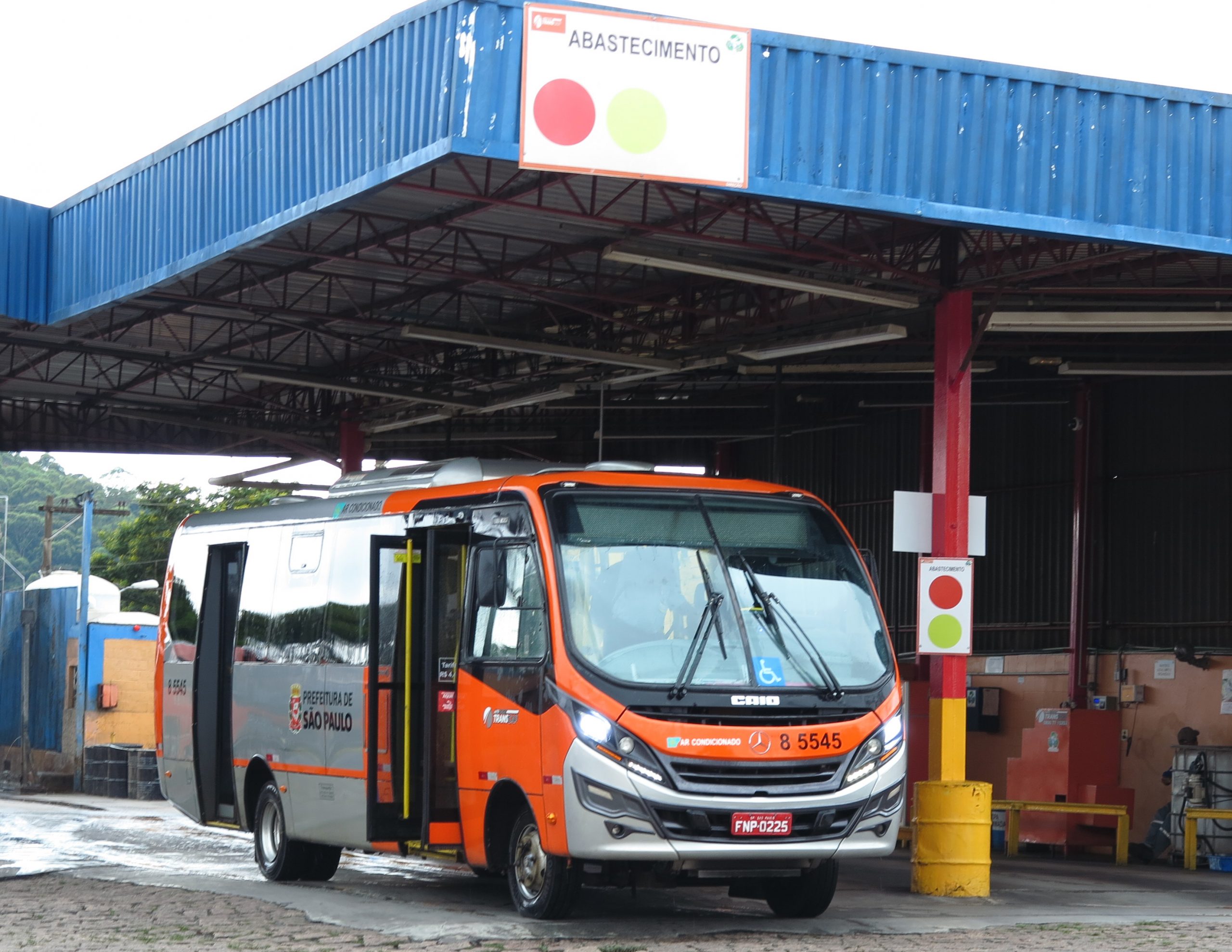 Ônibus do tipo "mini" estacionado para abastecimento em uma garagem de ônibus.